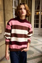 Buzo tejido de punto con diseño de rayas horizontales en tonos rosado, marrón y crema. Presenta cuello redondo alto y puños acanalados.