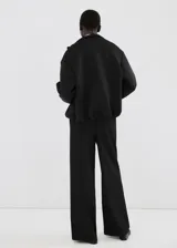 Pantalón negro de corte recto con franjas blancas laterales a lo largo de las piernas.