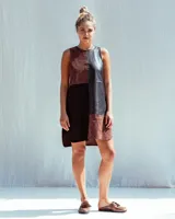 Vestido corto de corte recto y sin mangas, confeccionado en estilo patchwork con paneles de gamuza y cuero en tonos chocolate y negro. Presenta un diseño asimétrico y detalles bordados a tono en la parte frontal y trasera.