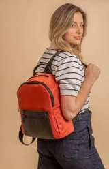 Mochila urbana de diseño combinado, confeccionada en tela resistente con bolsillo frontal y detalles en cuero sintético. Cuenta con compartimento principal con cierre y correas ajustables.