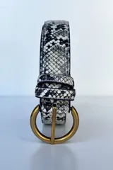 Cinto con estampado de piel de serpiente en tonos beige y negro, con hebilla circular dorada.