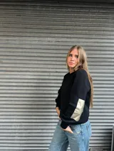 Sweater negro de lana merino con apliques rectangulares de cuero color plateado en los codos.