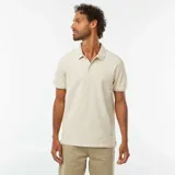 Remera tipo polo color beige claro, de piqué de algodón, con cuello clásico, tapeta de dos botones y mangas cortas.