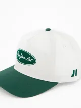 Gorra de béisbol blanca con visera verde y bordado frontal con la frase "Sign Your Art" en verde.