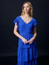 Vestido de gasa color azul con escote en V, manga corta con volados, corte en la cintura y falda larga con capas. Abertura central en la espalda con cierre invisible y forro interno a tono.