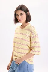 Sweater de punto fantasía color amarillo con líneas horizontales onduladas en color fucsia, de cuello redondo y manga corta.