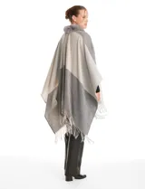 Ruana tejida con diseño color block en tonos grises y beige, con cuello de piel sintética y terminación en flecos.