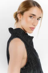 Chaleco de jean sin mangas con cuello en V y cierre frontal con botones metálicos. Tiene dos bolsillos de parche en el pecho y corte recto.