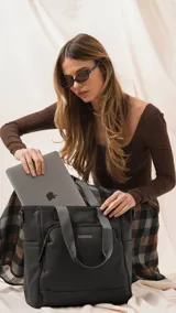Cartera tipo tote marrón de diseño práctico y versátil, confeccionada en símil cuero con textura granulada. Cuenta con asas cortas fijas, bolsillos exteriores con cierre al frente y atrás, y bolsillos laterales abiertos. Su interior es amplio e incluye bolsillos organizadores. Viene con una correa ajustable y desmontable.