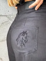 Pantalón sastrero de lino en color beige, de corte recto y tiro alto. Presenta un delicado bordado de un caballo en uno de los bolsillos traseros y costuras en contratono.