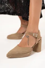 Sandalias de tacón color visón con puntera triangular y tira con hebilla al tobillo.