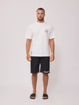 Remera blanca de algodón con cuello redondo y manga corta. Presenta un pequeño estampado frontal con el logo de Rusty y un diseño de tabla de surf.