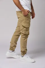Pantalón cargo color beige de gabardina, con corte ajustado, bolsillos laterales con fuelle y puños elásticos en los tobillos.