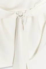 Top satinado color crema con cuello halter y lazada en la parte trasera. Presenta un escote drapeado asimétrico.