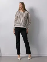 Blusa de gasa estampada con líneas verticales negras sobre fondo beige, de manga larga con puño abotonado. Espalda con abertura y botón.