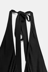 Vestido negro de largo midi, con escote halter que se anuda en la nuca, escote profundo en V con frunces y falda fluida.