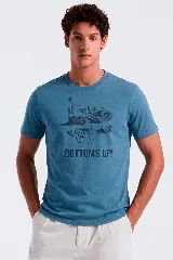 Remera celeste con estampado frontal en tonos oscuros que incluye elementos de juegos de azar como cartas, dados, fichas y un vaso, acompañado del texto "BOTTOMS UP!".