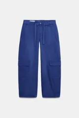 Pantalón cargo de tiro medio con corte oversize, bolsillos laterales con solapa en las piernas y bolsillos de plastrón en el delantero. Cuenta con trabillas, lazadas ajustables en la cintura y cierre frontal con cremallera y botón.