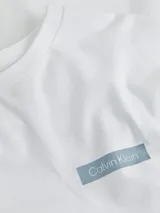 Remera blanca de manga larga con cuello redondo y logo de Calvin Klein estampado en el pecho.