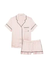 Pijama corta de satín con diseño de rayas verticales rosadas y blancas, ribetes negros en cuello, solapa, bolsillo y dobladillos. Consta de una camisa de manga corta con botones frontales y bolsillo en el pecho, y un short a juego con cintura elástica.