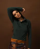 Sweater de punto fino en color verde oscuro, con cuello polo y cierre frontal de dos botones. Presenta un diseño ajustado al cuerpo y mangas largas.