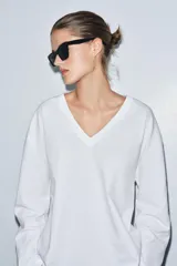 Camiseta blanca de algodón con escote en pico, manga larga y bajo recto.