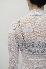 Remera negra de manga larga confeccionada en encaje, con cuello redondo y corte ajustado al cuerpo.