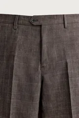 Pantalón de traje regular fit marrón con sutil estampado a cuadros, confeccionado en mezcla de lino y lana. Cuenta con bolsillos delanteros, bolsillos traseros de doble vivo con botón y raya marcada en el centro de las piernas.