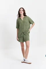 Camisa de manga corta color verde oliva, tejida con textura y diseño calado, con cuello clásico, botones y elástico en las mangas.