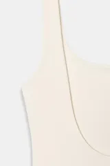 Body de tejido elástico color beige, con escote cuadrado y tirantes anchos.