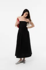 Vestido largo blanco con escote strapless y cuerpo fruncido. Posee falda amplia y fluida con bolsillos.