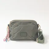 Bandolera de nylon color verde militar con múltiples compartimentos con cierre, correa ajustable de tela estampada y detalle de colgante con cuerdas decorativas.