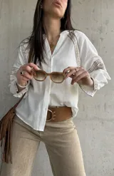 Camisa blanca de calce relajado y tejido liviano, con escote en V y delicados detalles bordados geométricos en tonos tostados en las mangas abullonadas y puños.