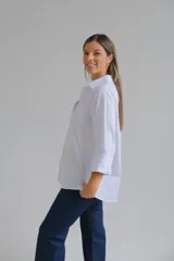 Camisa de corte clásico en color blanco, con cuello camisero, cierre frontal de botones y mangas largas con puños abotonados.