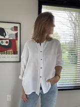 Camisa de manga larga de bambula de algodón, color blanco, con cuello mao, apliques de encaje en la pechera y botones frontales de coco. Diseño holgado.