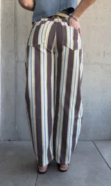 Jean modelo barrel de corte amplio, con diseño de rayas verticales en tonos marrón chocolate, celeste, tostado y blanco.