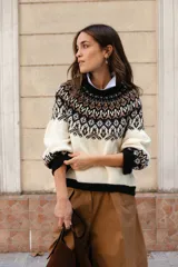 Sweater de lana con diseño de jacquard en la parte superior, cuello redondo, mangas largas y puños acanalados. Presenta un corte holgado con tajos laterales y un diseño ligeramente más corto en la parte delantera.