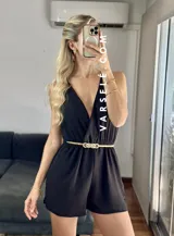 Mono corto negro con escote en V cruzado, sin mangas y con cinturón dorado.
