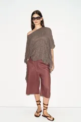 Top de cuello redondo color celeste con textura fruncida, mangas tipo capa y bajo asimétrico.