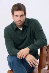 Buzo de felpa color verde oscuro, con cuello tipo polo, cierre frontal parcial con botones y bolsillos laterales. Presenta puños y ruedo acanalados.