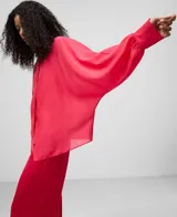 Camisa amplia semitransparente color blanco, con cuello chimenea y manga japonesa con puño. Presenta botonadura frontal oculta por solapa.