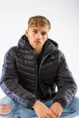 Campera puffer Mistral de nylon con relleno de guata, diseño capitoneado en color negro con paneles laterales en azul. Cuenta con capucha desmontable, cierre frontal y bolsillos con cierres personalizados, y logo de la marca en relieve en el pecho.