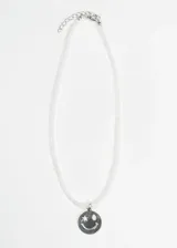 Collar de mostacillas blancas con dije plateado de carita sonriente con una estrella en el ojo.