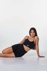 Conjunto deportivo de dos piezas color negro, compuesto por un top de tirantes finos con logo estampado y un short de tiro alto ajustado.