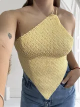 Top tejido al crochet color amarillo, con tirante fino y corte irregular.