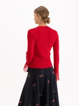 Top de tejido de punto fino color negro, con ajuste al cuerpo, cuello redondo y mangas largas que terminan en puños acampanados con detalle de tejido calado.