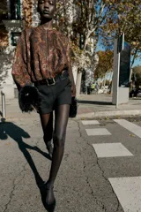 Falda pantalón negra de tiro medio con cierre frontal y hebilla metálica. Presenta bolsillos delanteros y falsos bolsillos de vivo en la espalda.