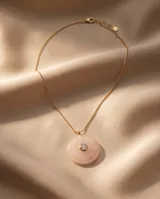 Collar de acero con baño de oro, compuesto por una cadena fina y un dije circular de cuarzo rosa natural con una circonia engastada en el centro.