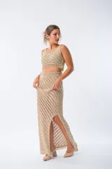 Conjunto de top y falda larga de tejido crochet color beige con diseño calado. El top es corto con breteles finos y flecos en el ruedo. La falda es larga con talle alto y abertura lateral.