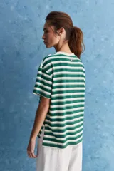 Remera de calce relajado con diseño a rayas horizontales blancas y verdes, hombros caídos y mangas amplias con vuelta. Presenta cuello redondo y ruedo trasero levemente más largo.